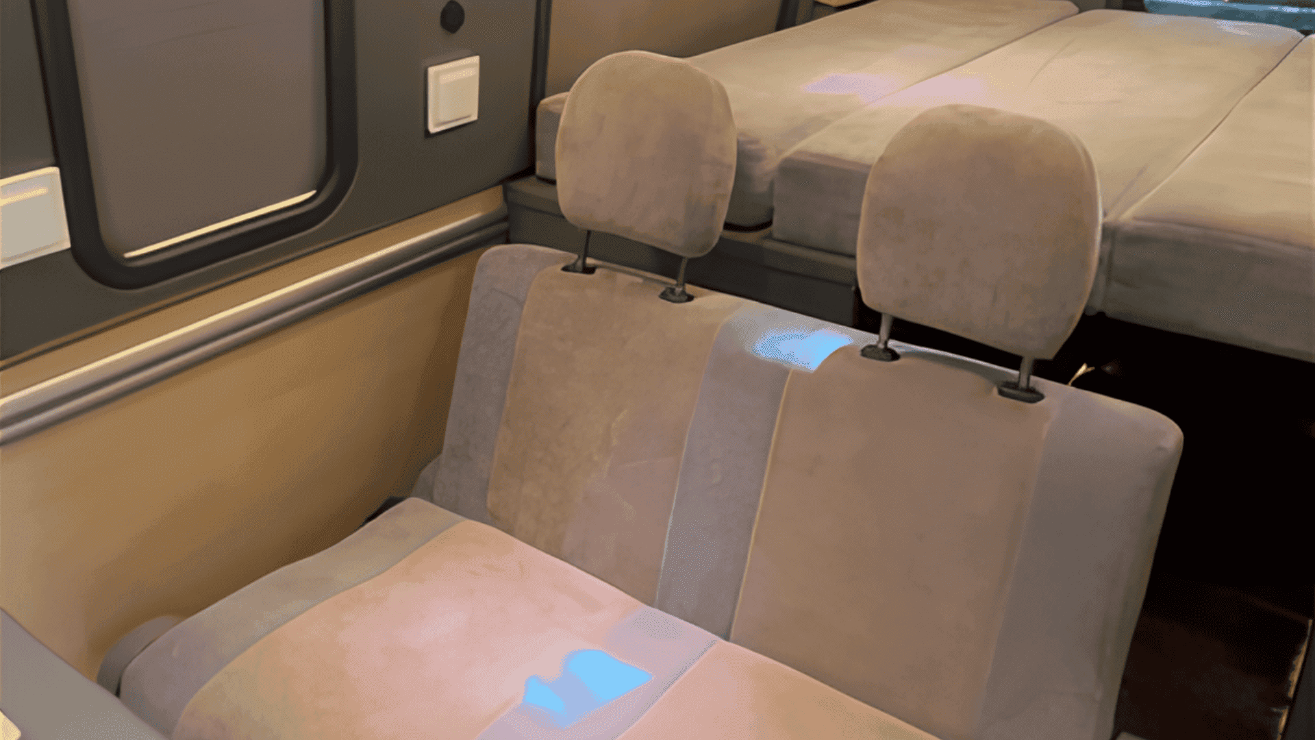 Neatly organized storage shelf under a campervan bed with a backpack
